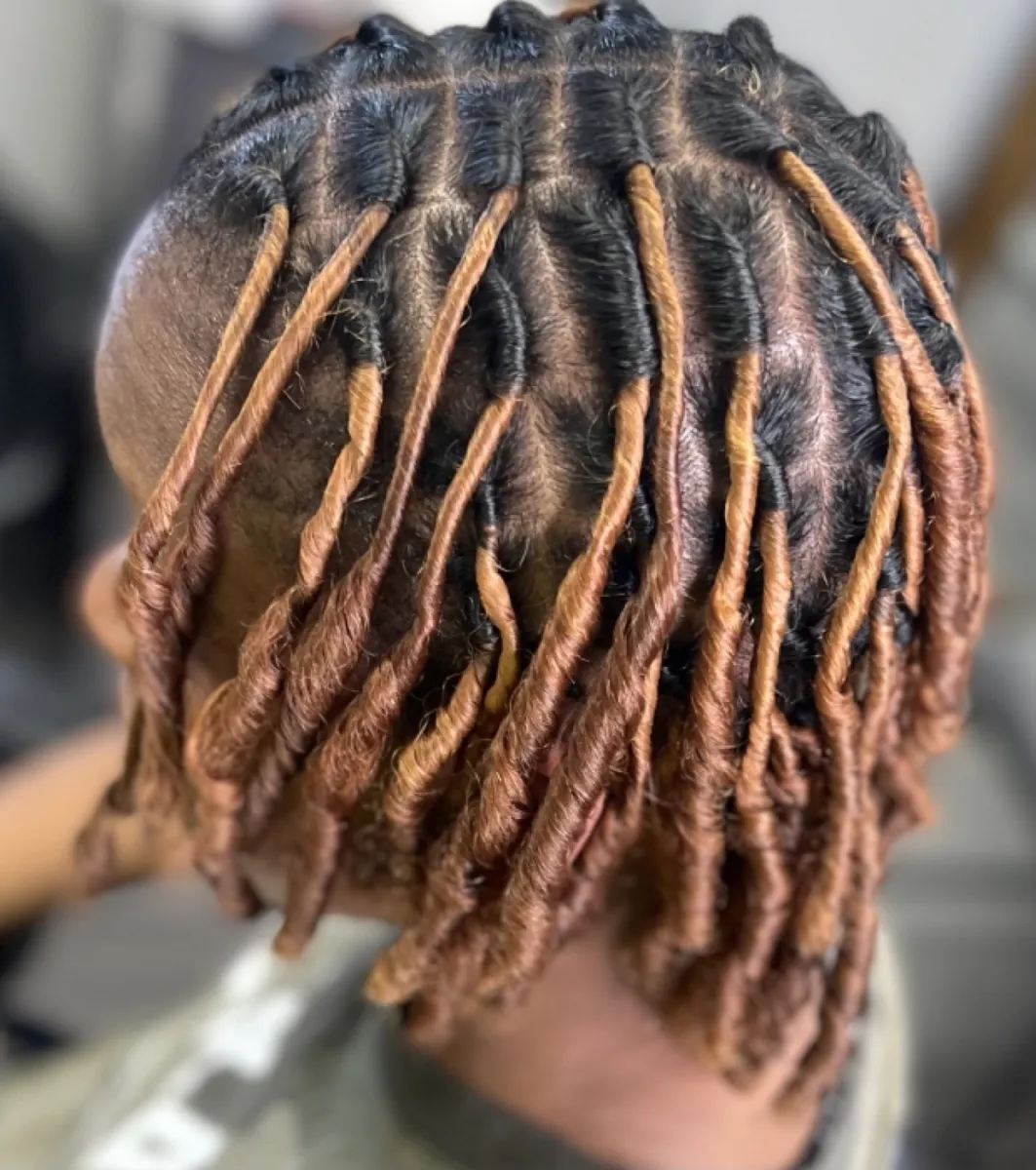 Starter locs sectioned into even rows and finished with warm copper tips.