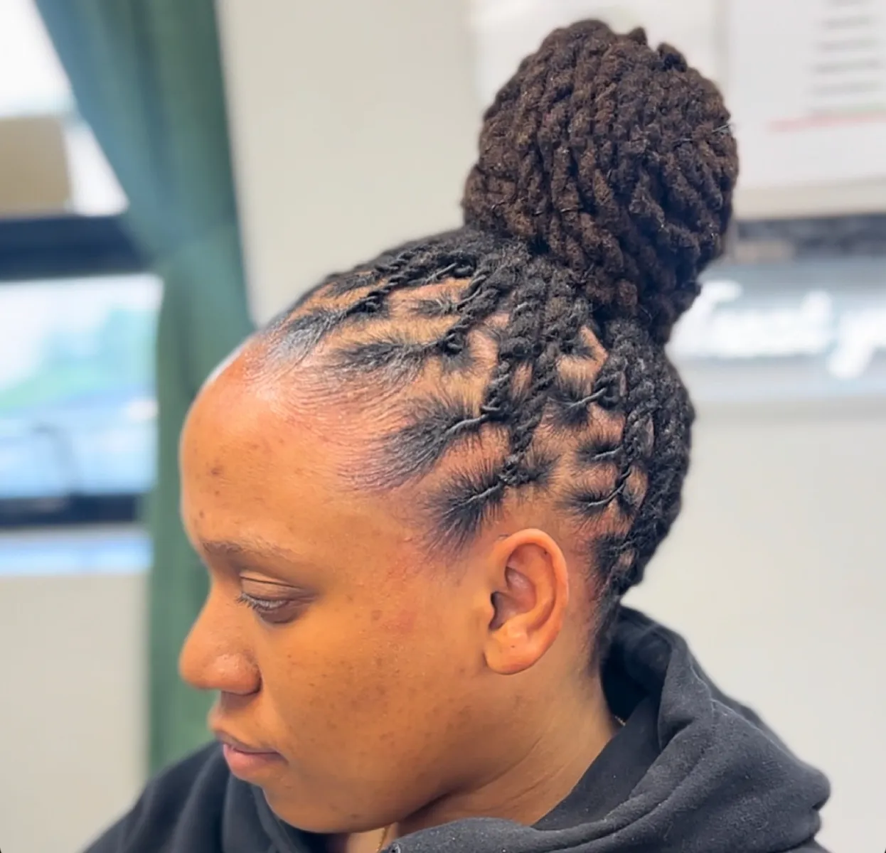 Two-strand loc style gathered into a high bun.