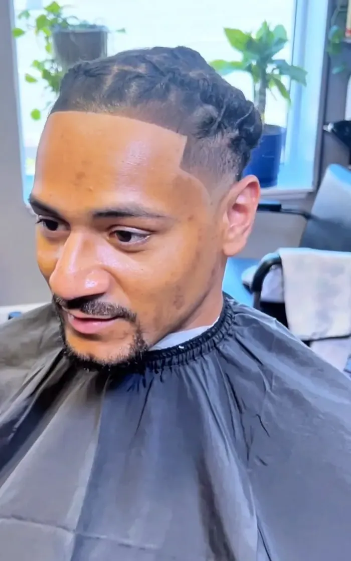 A curled twist crown over a clean shaved line-up and fade.