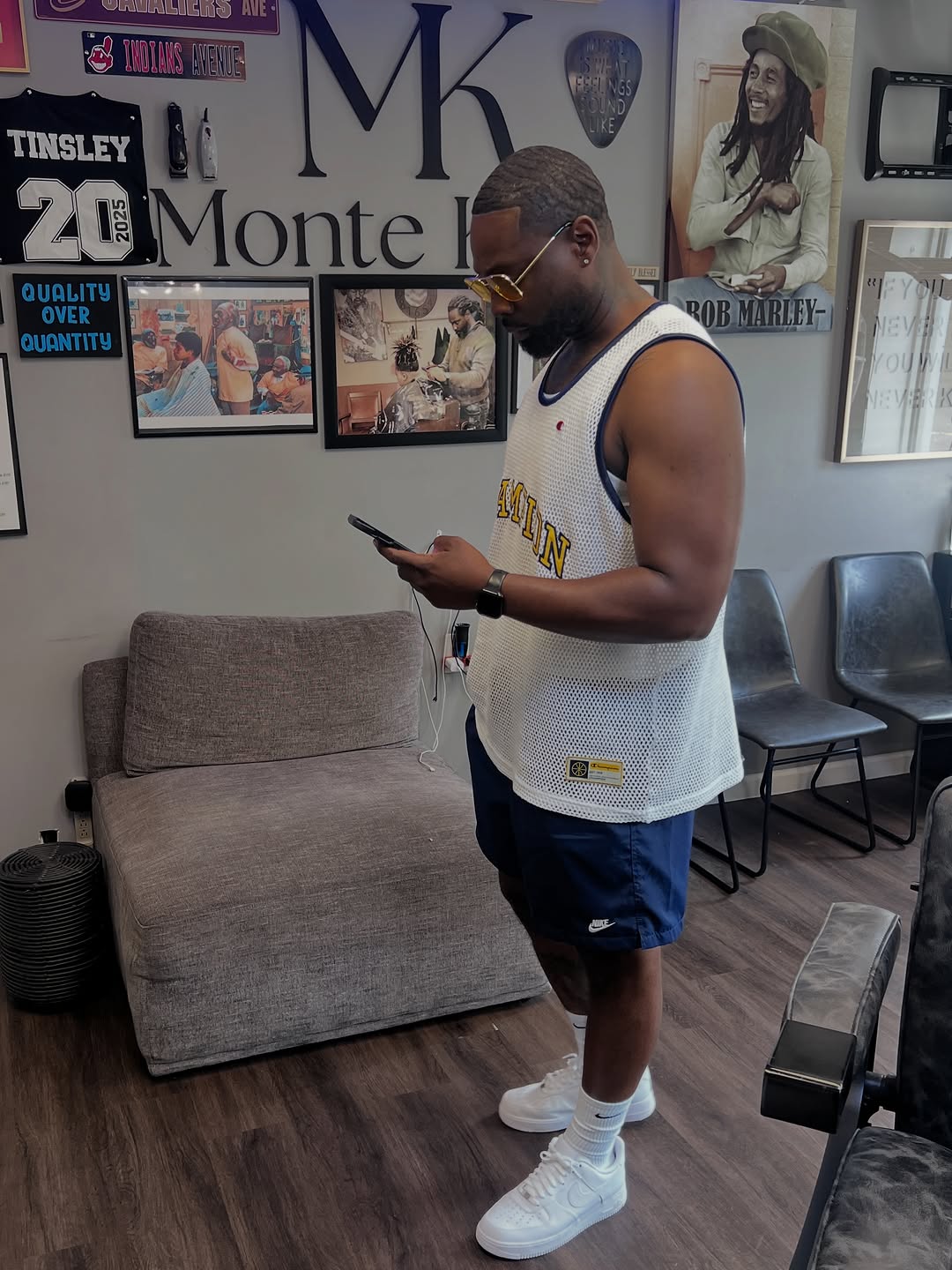Monte standing in his studio beneath the Monte Kuts wall sign and framed barbershop prints.